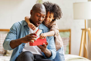 Happy Fathers day. African american kid son giving  gift box to dad for holiday at home